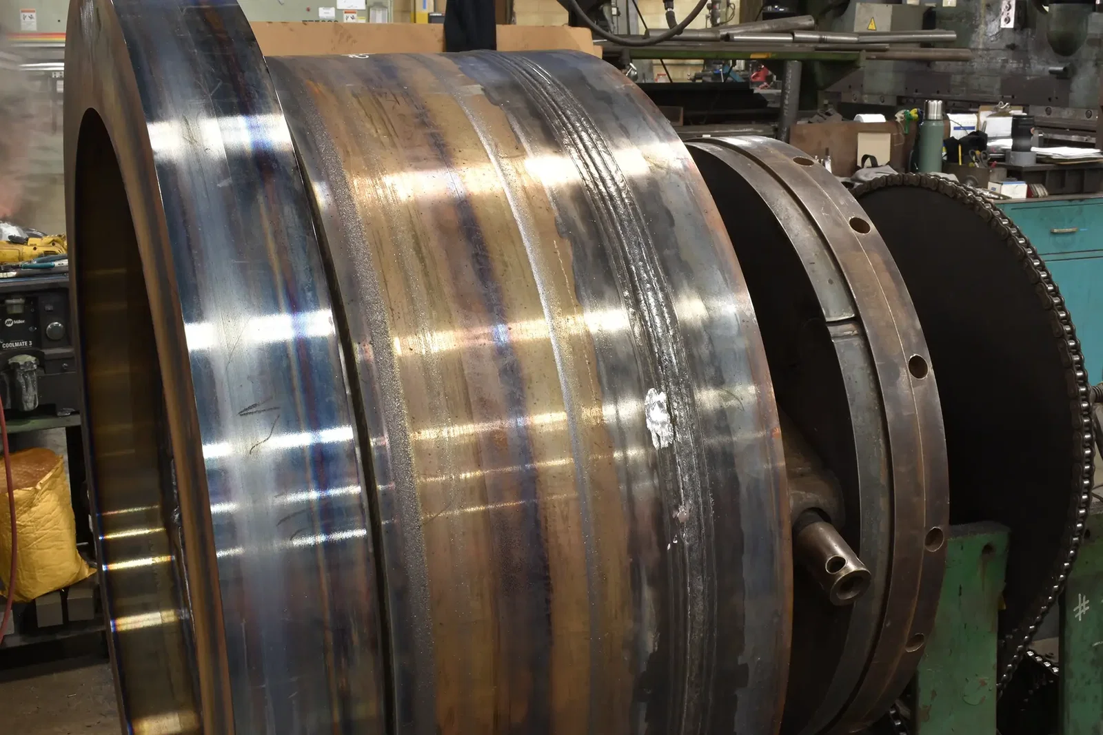Metal fabrication capabilities at Cutting Edge Fabrication — three-piece heavy equipment weldment in a welding stand on the Milwaukee shop floor