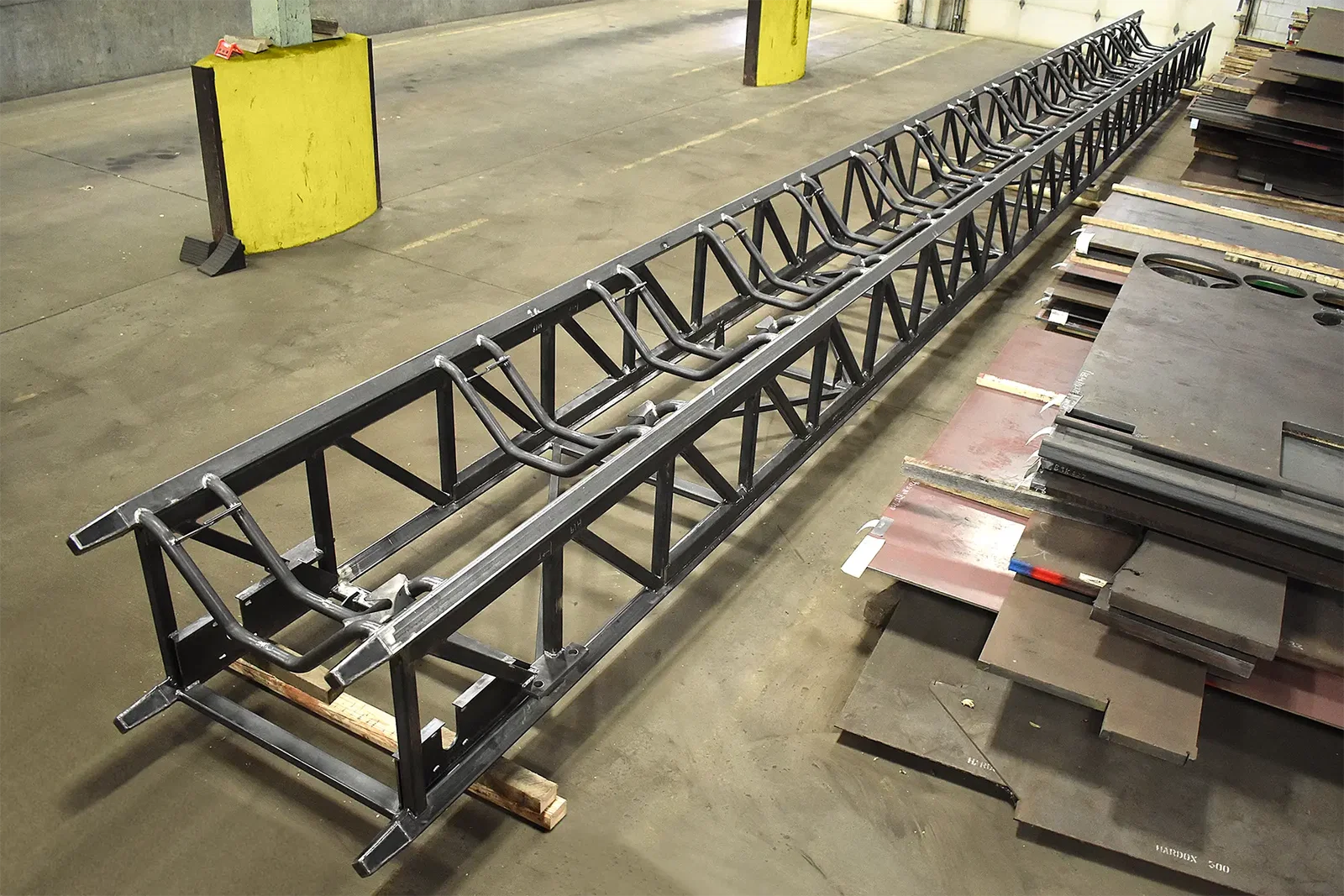 Seventy-foot telescopic conveyor base rail weldment on the shop floor at Cutting Edge Fabrication.